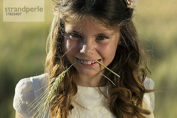 Lächelndes Mädchen  das Weizenernte im Mund hält