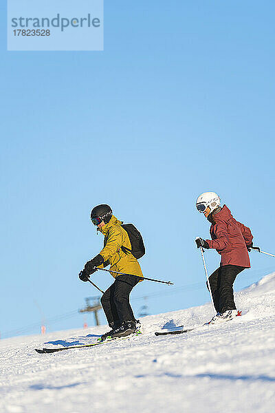 Couple skiing by blue sky in resort  Baqueira Beret  Pyrenees  Spain