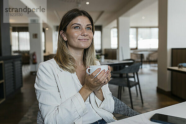 Lächelnde Geschäftsfrau hält Kaffeetasse im Restaurant