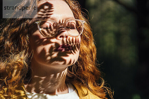 Frau mit geschlossenen Augen genießt das Sonnenlicht