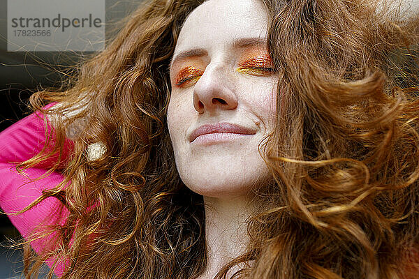 Lächelnde schöne rothaarige Frau mit orangefarbenem Lidschatten-Make-up