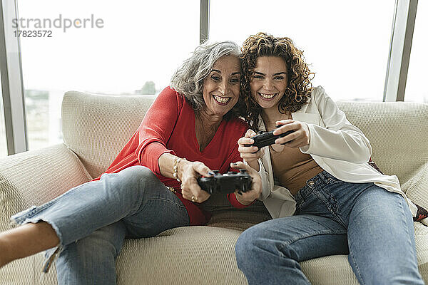Glückliche ältere Frau mit einem Freund  der Videospiele spielt