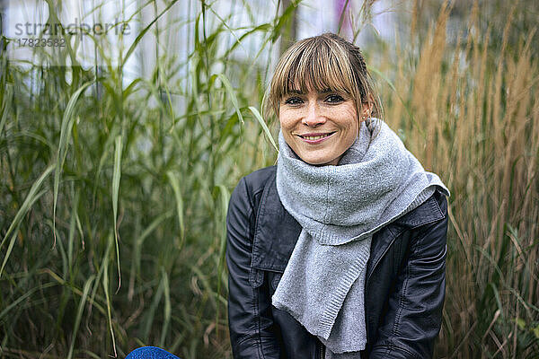 Lächelnde Frau mit Schal vor Gras auf dem Feld