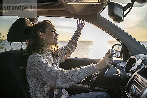 Glückliche junge Frau sitzt auf dem Fahrersitz im Auto