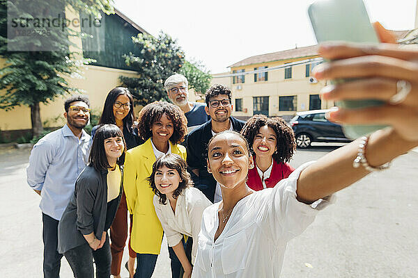 Lächelnde Geschäftsfrau  die ein Selfie mit multiethnischen Geschäftskollegen macht