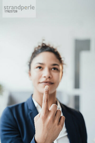 Lächelnde junge Geschäftsfrau zeigt mit dem Finger