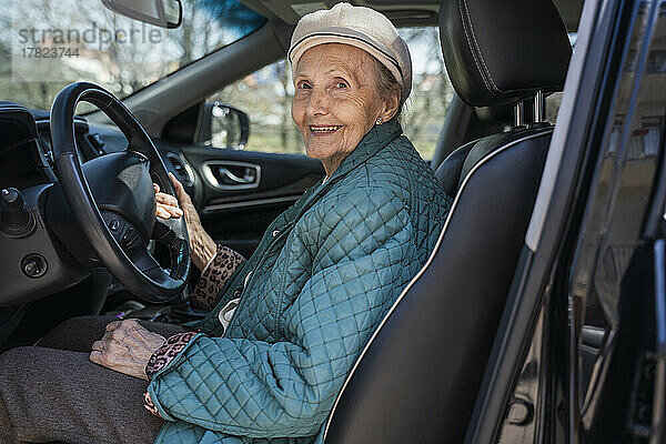 Lächelnde ältere Frau sitzt im Auto