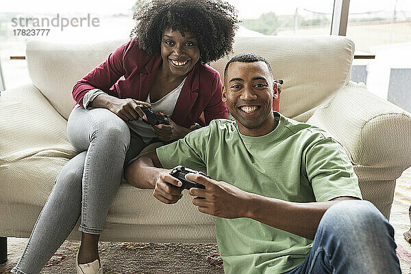 Lächelnde junge Frau spielt Videospiel mit Mann
