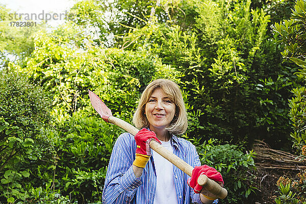 Lächelnde Frau mit Schaufel im Garten