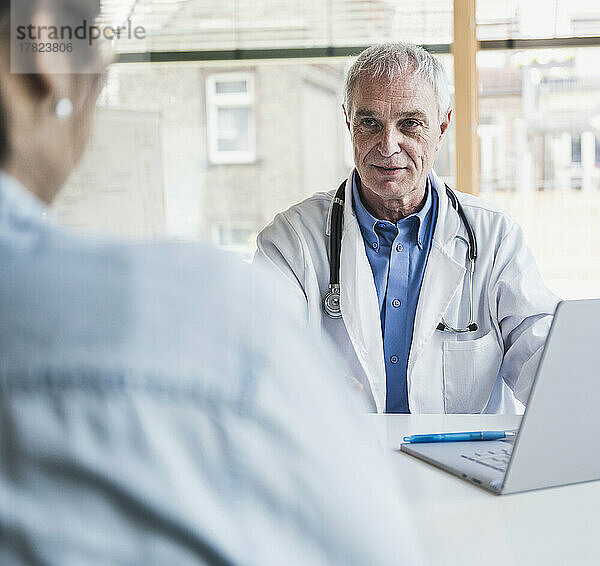 Leitender Arzt diskutiert mit Patient im Krankenhaus