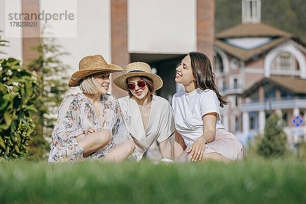 Freundinnen sitzen im Park und tragen Hüte  Sohn  sonniger Tag
