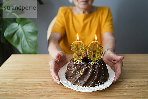 Senior woman with birthday cake sitting at table