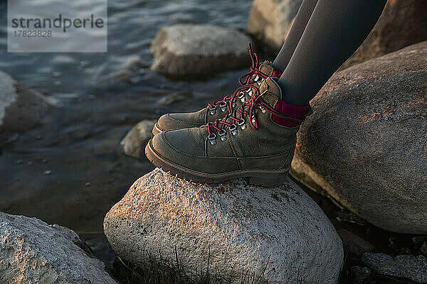 Beine einer Frau mit Schuhen auf einem Felsen