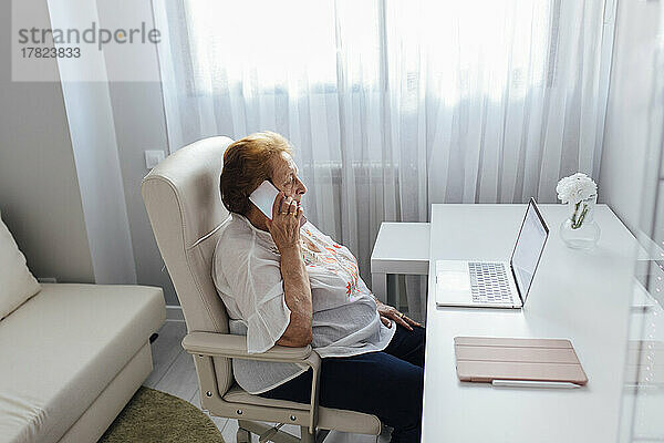 Ältere Frau spricht zu Hause mit dem Smartphone