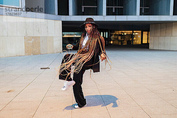 Junge Geschäftsfrau tanzt vor Bürogebäude