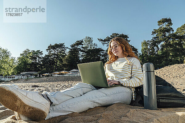 Frau beim E-Learning über Laptop am Strand