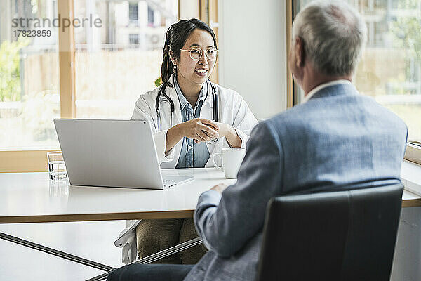 Glückliche Ärztin diskutiert mit Patientin in der medizinischen Klinik