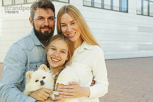 Glückliche Familie mit Hund steht vor dem Gebäude
