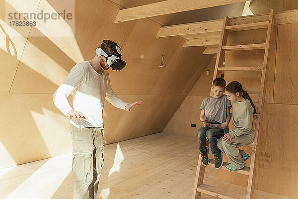 Mann mit 3D-Brille und Kindern visualisiert die Inneneinrichtung eines neuen Öko-Hauses