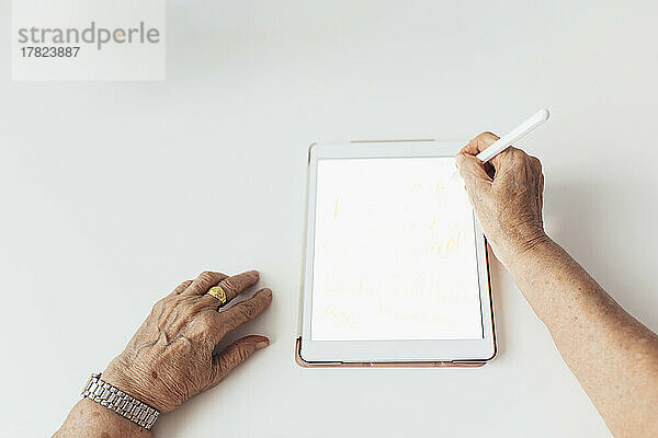 Hände einer älteren Frau mit Tablet-PC vor weißem Hintergrund