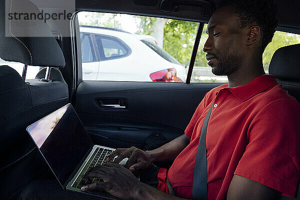 Mann mit Laptop sitzt im Auto