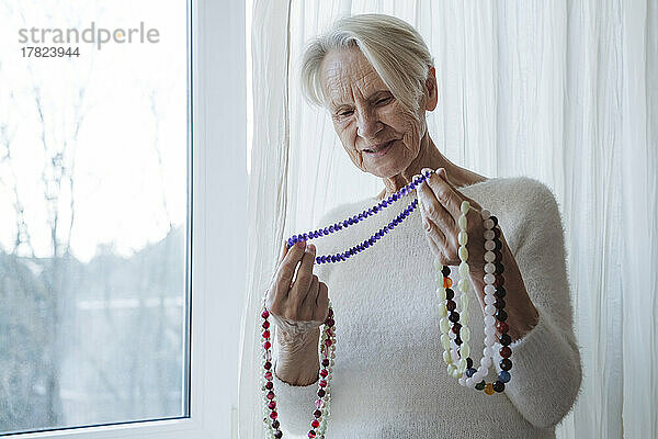 Glückliche ältere Frau mit Edelsteinperlen-Halskette