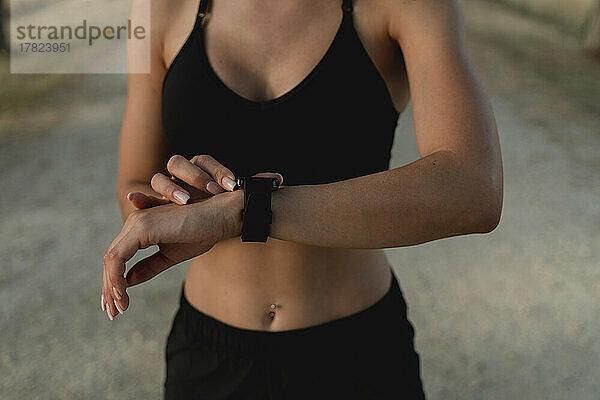 Junge Frau überprüft die Uhrzeit mit einer Smartwatch