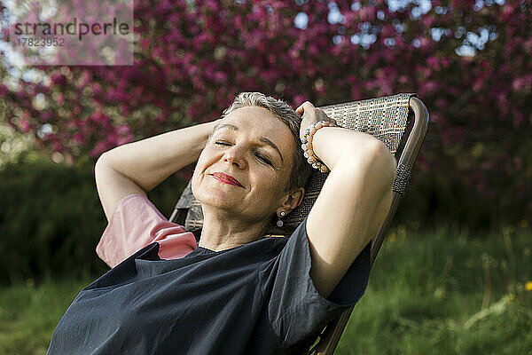 Smiling woman with eyes closed resting in garden
