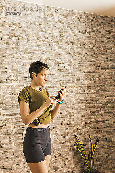 Frau benutzt Smartphone vor Wand
