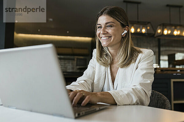 Lächelnde Geschäftsfrau benutzt Laptop im Restaurant