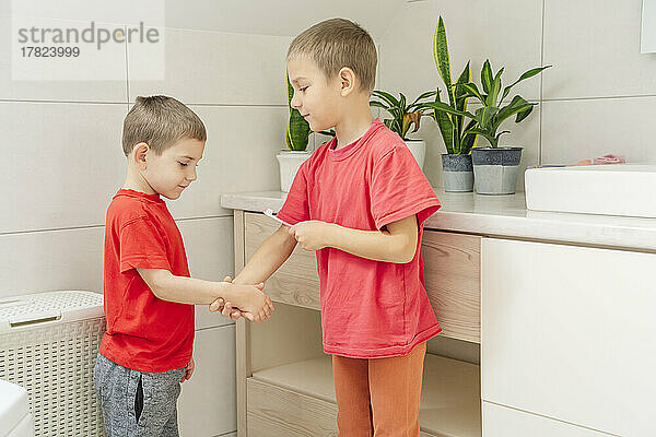 Junge bringt seinem Bruder bei  im Badezimmer Zähne zu putzen