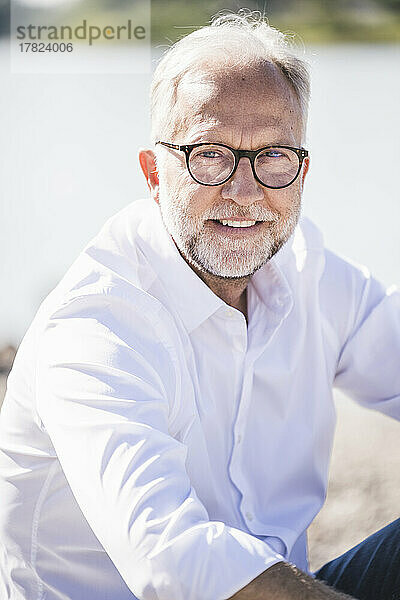 Lächelnder älterer Mann mit Brille an sonnigem Tag