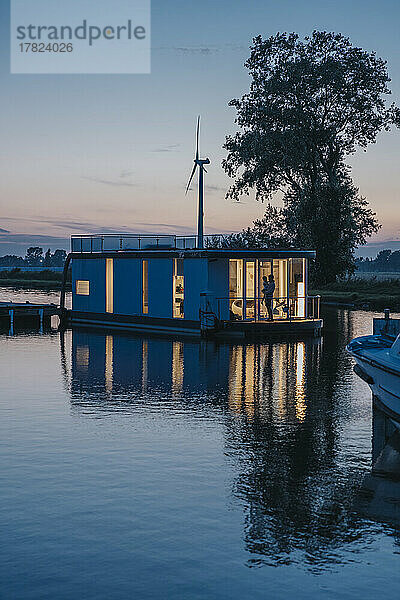 Beleuchtetes Hausboot mit Spiegelung am Yser-Fluss bei Sonnenuntergang