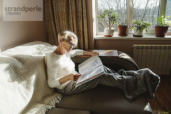 Frau mit Brille liest zu Hause Dokumente