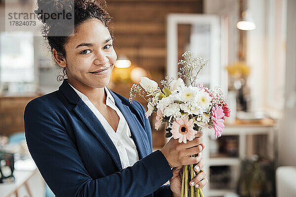 Lächelnde junge Geschäftsfrau mit Blumen im Büro