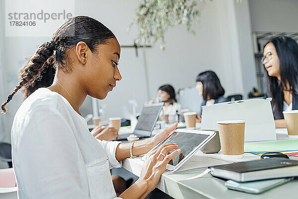 Geschäftsfrau arbeitet am Schreibtisch im Coworking Space am Tablet-PC