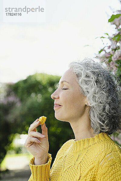 Glückliche Frau isst Makronen im Park