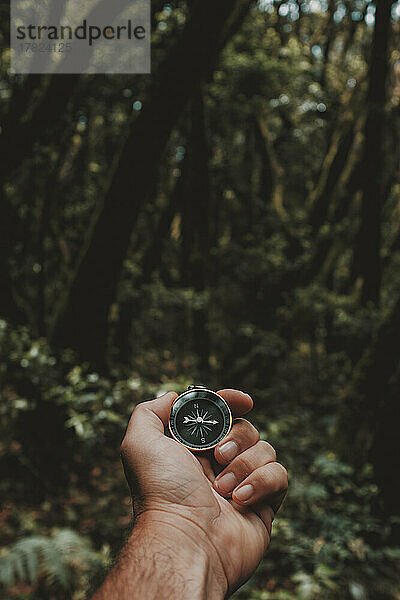 Hand eines reifen Mannes mit Navigationskompass im Wald