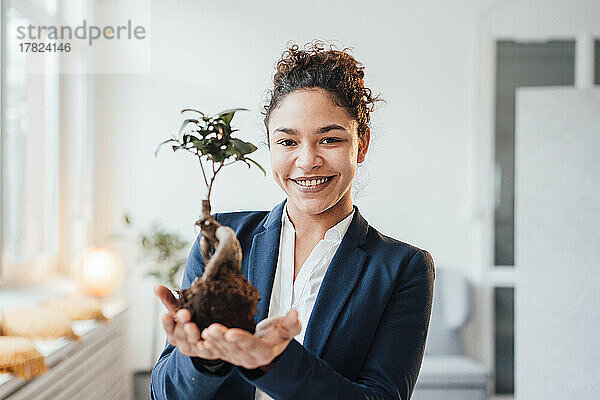 Glückliche Geschäftsfrau mit Pflanze im Büro