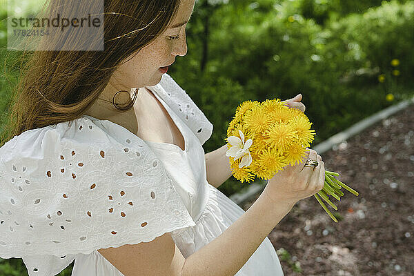 Schwangere Frau mit Blumen steht im Park