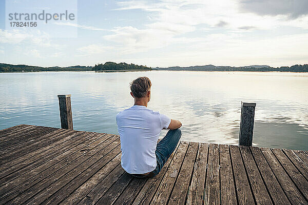 Mann blickt vom Pier auf die malerische Aussicht auf den See