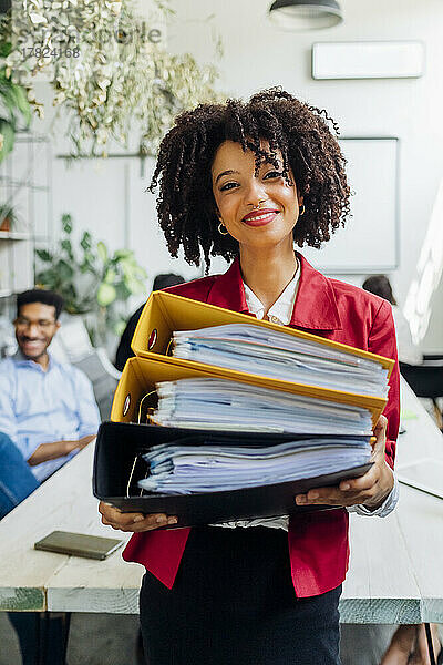 Lächelnde Geschäftsfrau hält Akten im Büro