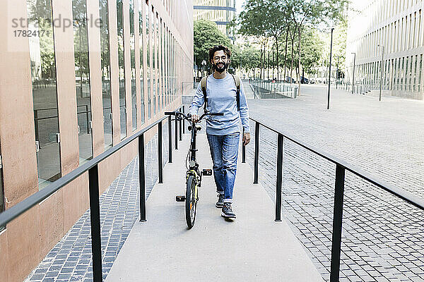 Mann mit Fahrrad läuft auf Bürgersteig in der Stadt