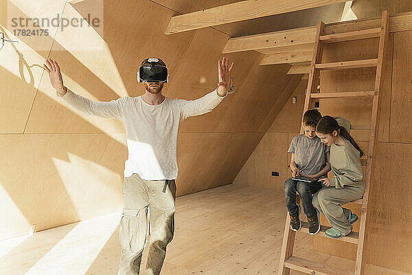 Mann mit 3D-Brille und Kindern visualisiert die Inneneinrichtung eines neuen Öko-Hauses