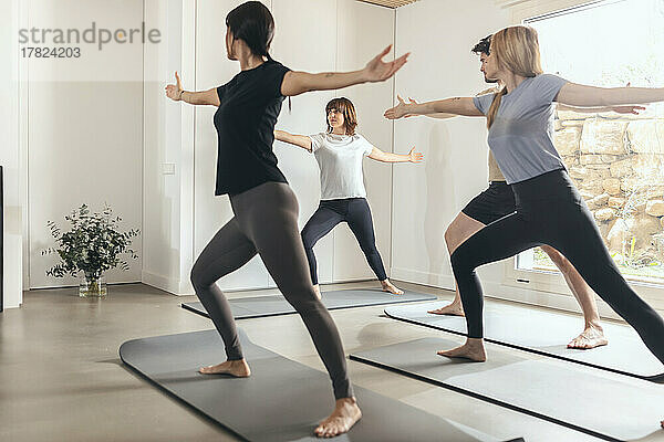 Männer und Frauen praktizieren Yoga mit einem Lehrer im Fitnessstudio