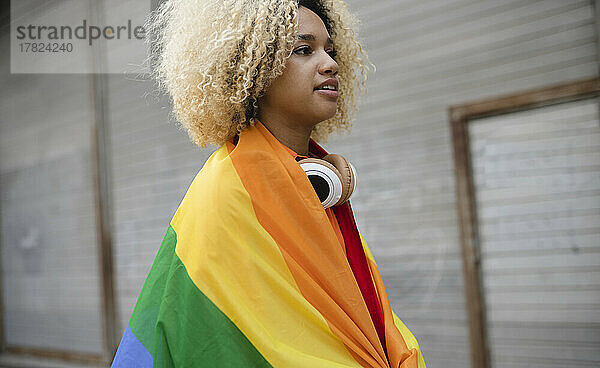 Frau mit lockigem Haar  bedeckt mit Regenbogenfahne