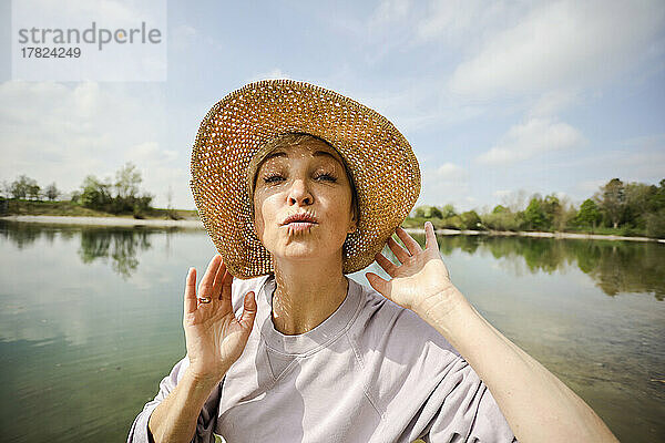 Reife Frau mit Hut macht an einem sonnigen Tag kräuselnde Lippen