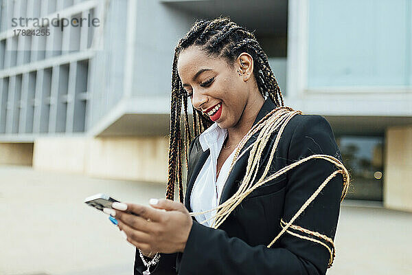 Glückliche junge Geschäftsfrau  die Mobiltelefon benutzt