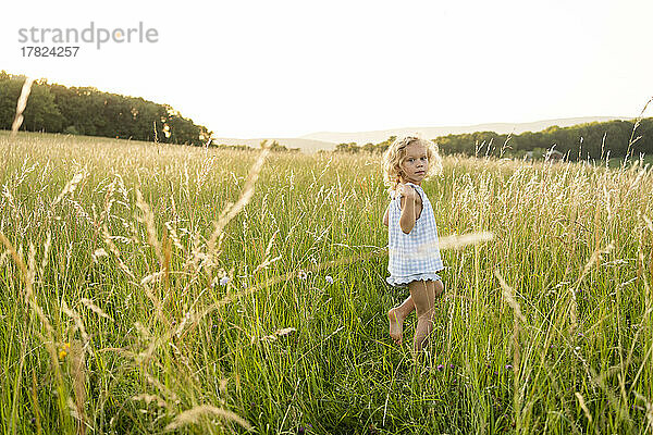 Blondes Mädchen läuft inmitten von Gras im Feld