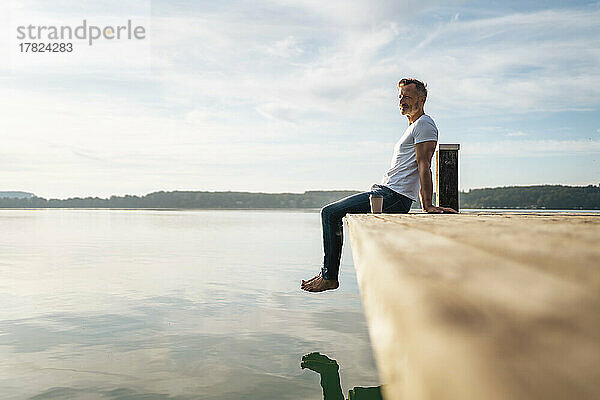 Reifer Mann blickt vom Pier aus auf die Aussicht